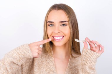 young woman holding retainer and smiling clipart