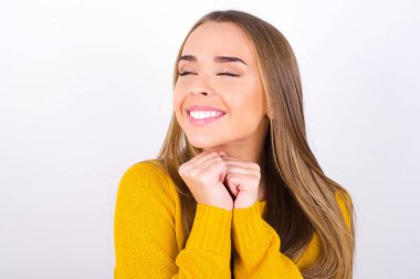 Stüdyoda gözleri kapalı gülümseyen genç bir kadının portresi.