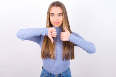 Genç bir kadın baş parmağını kaldırıyor ve baş parmağını eğiyor. 