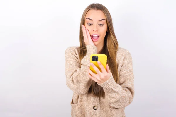 Young Woman Posing Smartphone Studio Looking Screen Surprised Face — Stockfoto