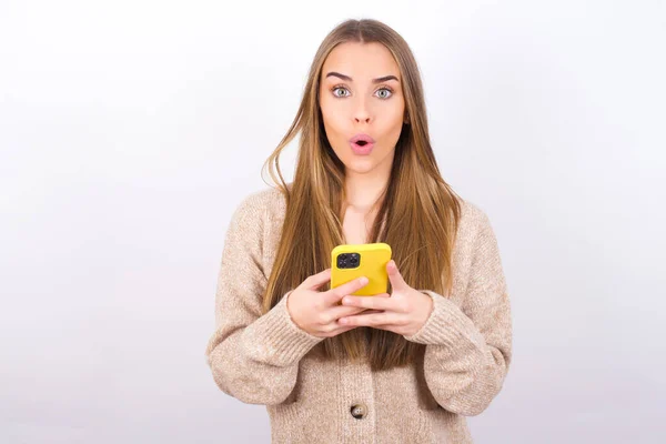 Mujer Joven Sosteniendo Teléfono Inteligente Estudio Con Cara Sorprendida — Foto de Stock