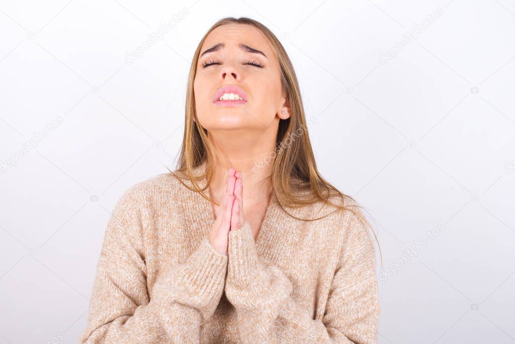 young woman praying with hands with begging face expression