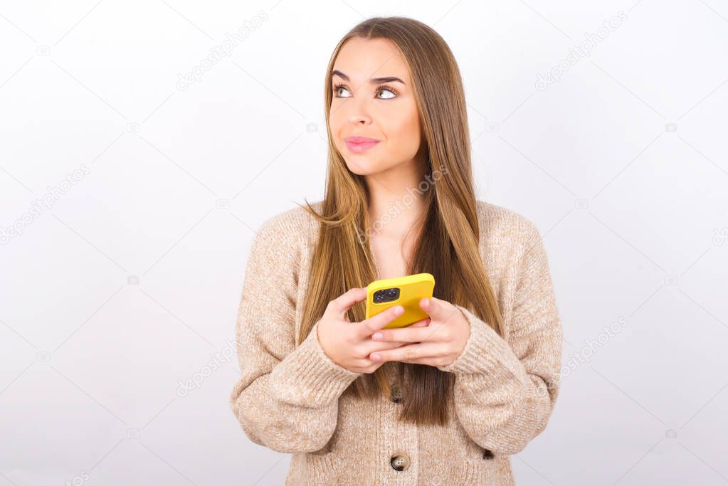 young woman posing with smartphone in studio looking away