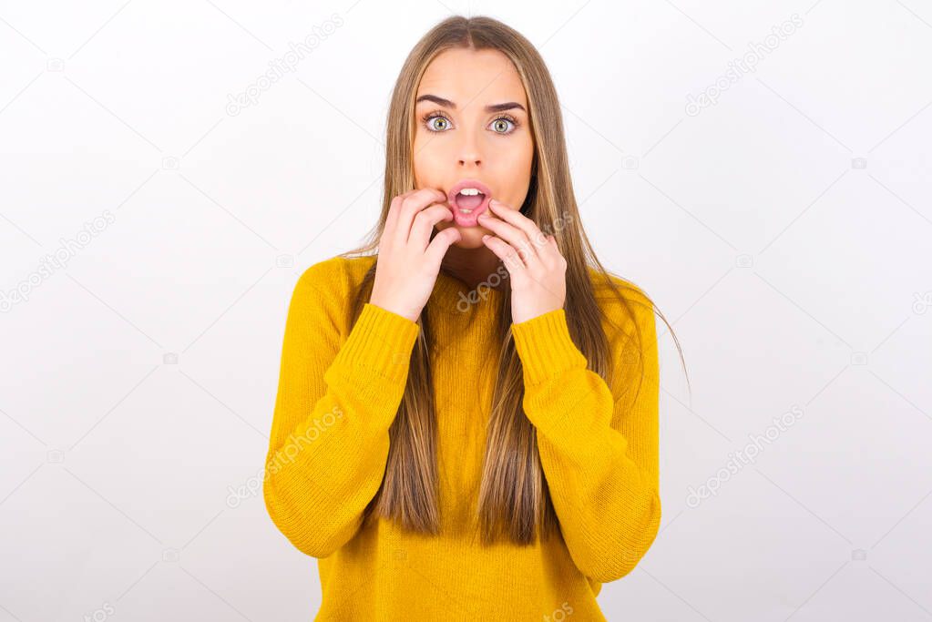 scared young woman with wide open eyes and hands by face