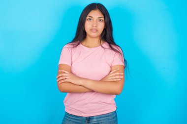 Mavi arka planda pembe tişört giyen kızgın İspanyol kızın fotoğrafı..