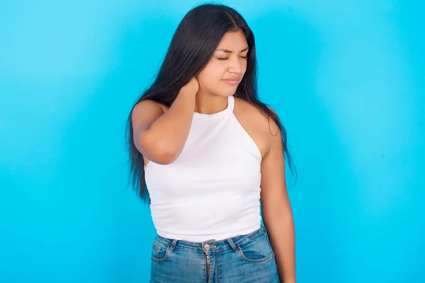 Young Hispanic Girl Wearing White Tank Top Blue Background Suffering — 图库照片