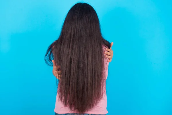 Joven Chica Hispana Con Camiseta Rosa Sobre Fondo Azul Abrazándose —  Fotos de Stock