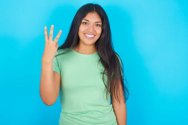 Mladá Hispánka Zeleném Tričku Přes Modré Pozadí Usmívá Vypadá Přátelsky — Stock fotografie
