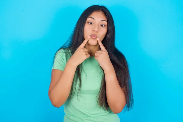 Jong Hispanic Meisje Dragen Groen Shirt Blauwe Achtergrond Kruist Ogen — Stockfoto