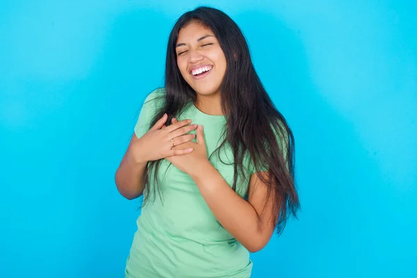 Mladá Hispánka Zeleném Tričku Přes Modré Pozadí Vyjadřuje Štěstí Příjemně — Stock fotografie
