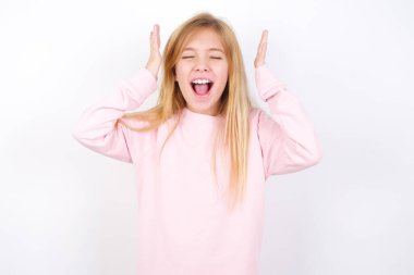 Beyaz arka planda pembe süveter giyen güzel beyaz bir kız korkunç bir durum yüzünden stres altındayken deliriyor.