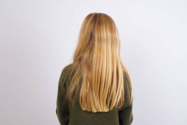 Beyaz arka planda yeşil örülü süveter giyen beyaz bir kızın arka plan görüntüsü. Stüdyo Çekimi.