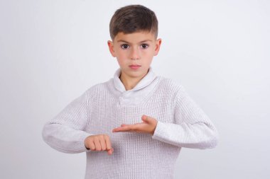 Beyaz arka planda dikilen örülü süveter giyen beyaz çocuk saati, sabırsızlığı ve gecikmeyi işaret ederek acele ediyor..