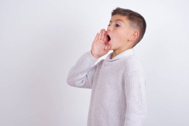 Beyaz arka planda dikilen örgü kazak giyen beyaz çocuk el ele tutuşarak bağırıyor ve çığlık çığlığa bağırıyordu. İletişim konsepti.