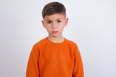 Beyaz arka planda dikilen örülü turuncu süveter giyen Kafkasyalı çocuk üzgün. Ağlayacak gibi, hoşnutsuz ve mutsuz. Hedeflere ulaşamadığı için hayal kırıklığına uğramış modelin sorunları var.