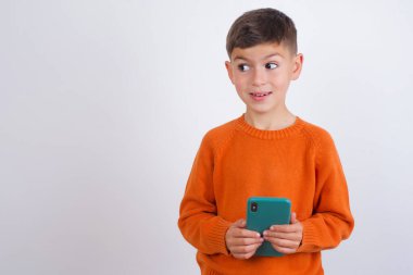 Beyaz arka planda dikilen örgü turuncu süveter giyen beyaz çocuk sosyal medyada bir şey belirdi.