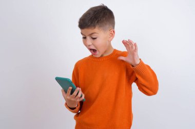 Beyaz arka planda dikilmiş örgü turuncu süveter giyen kızgın beyaz çocuk telefonda bir çalışanla tartışıyor. İşte sorunlar var..