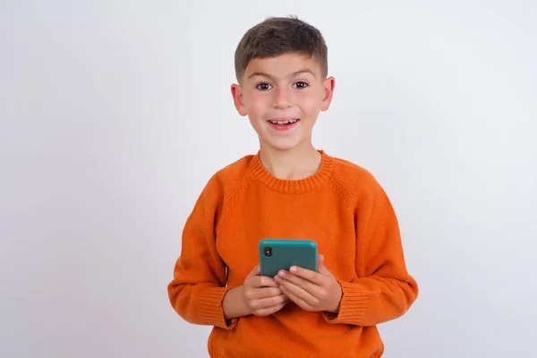 Emocionado Niño Caucásico Usando Suéter Naranja Punto Pie Sobre Fondo —  Fotos de Stock