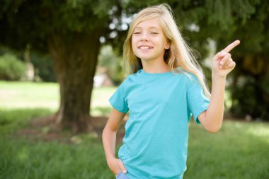 Beyaz, mavi tişörtlü kız dışarıda dikilip kameraya bakarak boş uzay satışlarını gösteriyor.