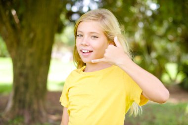 Güzel, beyaz, sarı tişörtlü kız dışarıda dikiliyor, telefon ediyor, 