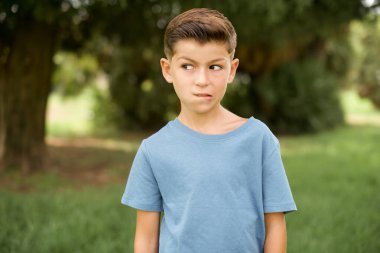 Mavi tişört giyen, dudak ısıran ve uzayı boşaltmak için kurnaz görünen beyaz çocuk..