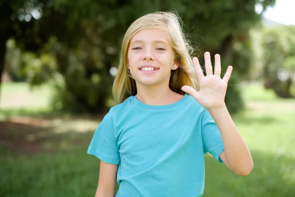 Caucásico Niña Pequeña Vistiendo Azul Camiseta Pie Aire Libre Mostrando — Foto de Stock