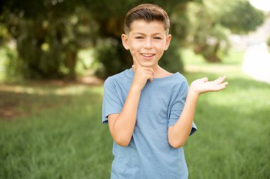 Açık havada duran mavi tişörtlü komik, güzel, beyaz çocuk. Avuç içi yeni ürünler tutuyor. Harika bir öneri.