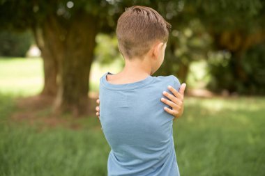 Güzel beyaz çocuk mavi tişört giymiş mutlu ve pozitif bir şekilde kendine sarılıyor. Sevgi ve özgüven.