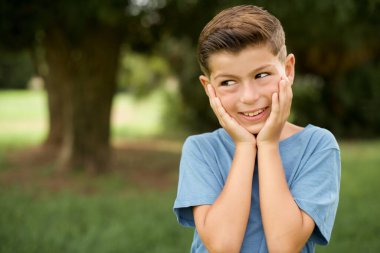 Mavi tişörtlü güzel, beyaz bir çocuk. Kopyalama alanına bakıyor. Gelecekle ilgili düşünceleri var.