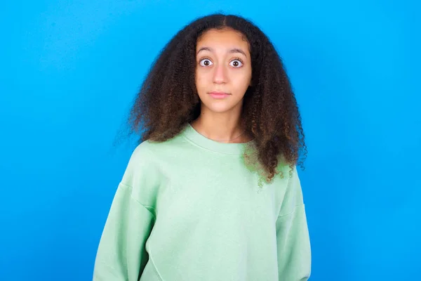 Oszałamiająca Piękna Nastolatka Zielonym Swetrze Stojąca Niebieskim Tle Reaguje Szokujące — Zdjęcie stockowe
