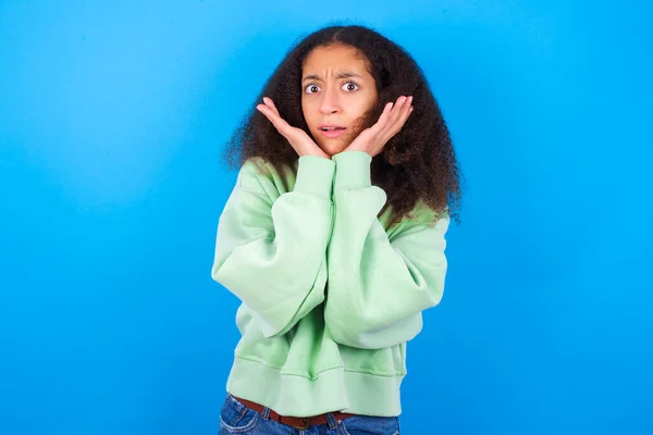Zdenerwowany Piękny Nastolatek Dziewczyna Noszenie Zielony Sweter Stoi Niebieskim Tle — Zdjęcie stockowe