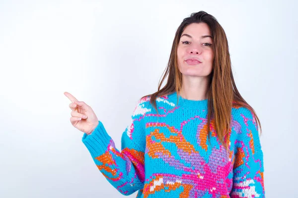 Positive Young caucasian woman wearing vintage colorful sweater over white background with satisfied expression indicates at upper right corner shows good offer suggests to click on link