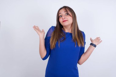 Belki evet ya da hayır. Şüpheli genç Arap kadın beyaz sırt çantasının üzerine mavi elbise giyip şaşkınlık içinde omuz silkiyor, ne istediğine karar vermeye çalışıyor. Tereddüt ve belirsizlik.