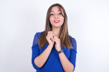 Hayalperest genç Arap kadın, beyaz sırt çantasına mavi elbise giyip hoş bir ifade takınıyor, ellerini yüzüne çapraz tutuyor, hoş bir şey için heyecanlanıyor..