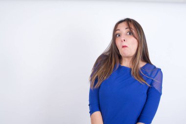 Genç Arap kadın, beyaz sırt çantasına mavi elbise giymiş, züppe ifadeli, kıvrık dudaklı, kaşlarını kaldıran şüpheli ve şüpheci bir ifadeyle şüpheli ve şüpheci bir ifadeyle bakıyor..