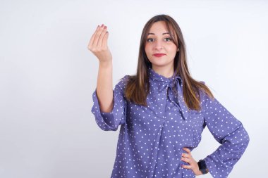 What the hell are you talking about. Shot of frustrated Young arab woman wearing polka-dot clothes over white backgtound gesturing with raised hand doing Italian gesture, frowning, being displeased and confused with dumb question.