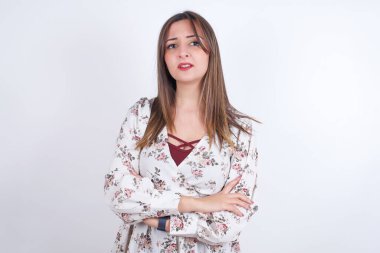 Beyaz sırt çantasına çiçek desenli gömlek giyen genç Arap kadın hoşnutsuzca yüzünü buruşturmuş, kollarını kavuşturmuş, bir açıklama bekliyor..