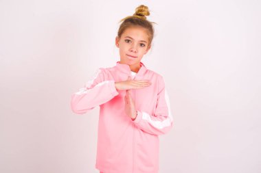 little caucasian kid girl wearing sport clothing over white background being upset showing a timeout gesture, needs stop, asks time for rest after hard work, demonstrates break hand sign