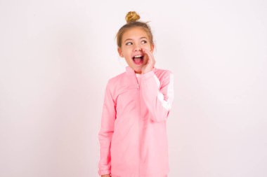 little caucasian kid girl wearing sport clothing over white background hear incredible private news impressed scream share