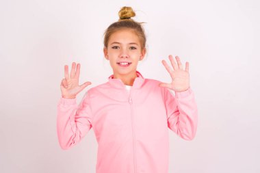 little caucasian kid girl wearing sport clothing over white background showing and pointing up with fingers number nine while smiling confident and happy.