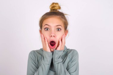 Scared terrified little caucasian kid girl wearing sport clothing over white background shocked with prices at shop, People and human emotions concept