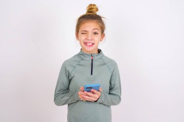 little caucasian kid girl wearing sport clothing over white background taking a selfie  celebrating success