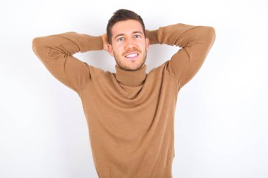 young caucasian man wearing turtleneck over white background stretching arms, relaxed position.