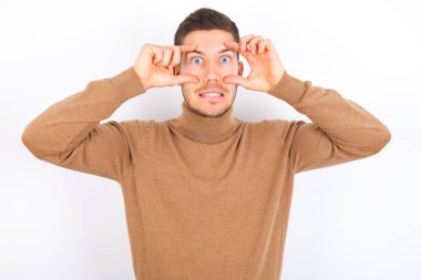 young caucasian man wearing turtleneck over white background keeping eyes opened to find a success opportunity.