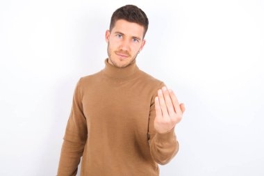 young caucasian man wearing turtleneck over white background inviting to come with hand. Happy that you came
