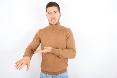 young caucasian man wearing turtleneck over white background In hurry pointing to watch time, impatience, upset and angry for deadline delay.