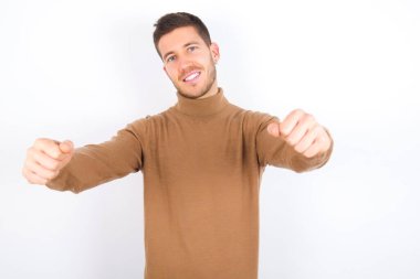 young caucasian man wearing turtleneck over white background imagine steering wheel helm rudder passing driving exam good mood fast speed