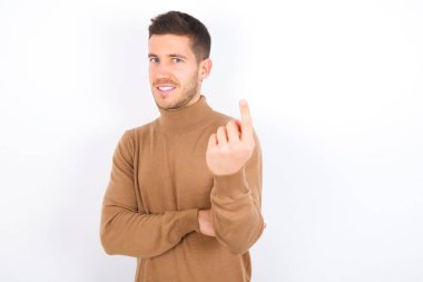young caucasian man wearing turtleneck over white background Beckoning come here gesture with hand inviting welcoming happy and smiling