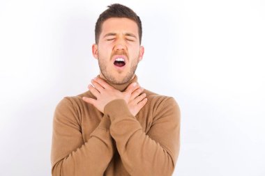 young caucasian man wearing turtleneck over white background shouting suffocate because painful strangle. Health problem. Asphyxiate and suicide concept.