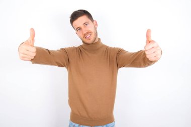young caucasian man wearing turtleneck over white background approving doing positive gesture with hand, thumbs up smiling and happy for success. Winner gesture.